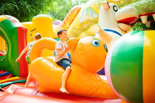 Happy boy having a lots of fun on a colorful inflate castle. Colorful playground. Activity and play center for kids.