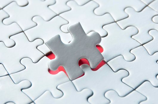 White jigsaw puzzle on red cover background with customizable space for text. Copy space and puzzle concept