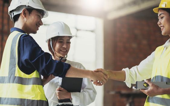 Male civil engineer or architect hand shake with contractor after discussing about designing of building styles and inspect progress of housing project at construction sites. Worker work in real estate