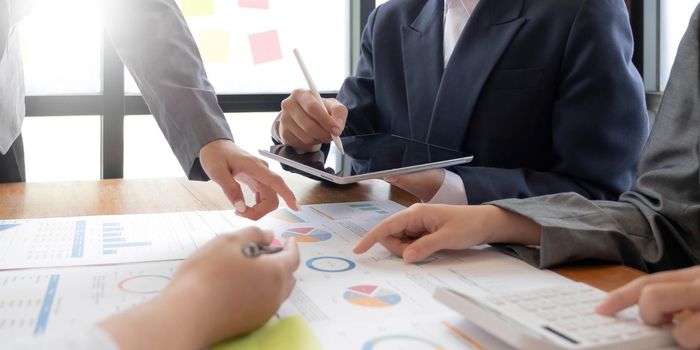 businessmen and woman sitting, working and discussing questions at meeting in modern office, close-up.