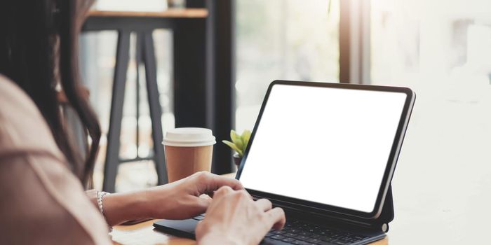 Side view of a businesswoman working on a laptop blank white screen at office. Mock up..