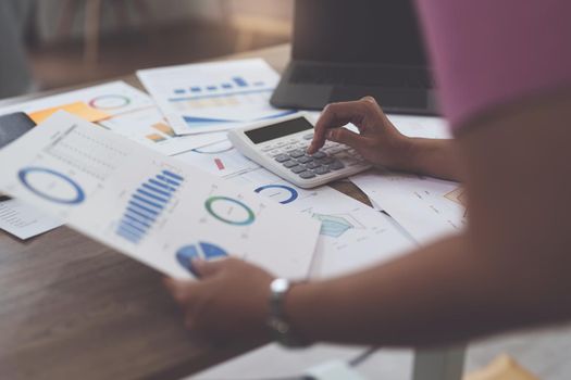 Business woman hand using calculator to calculate the company's financial results and budget. Account Audit Concept.