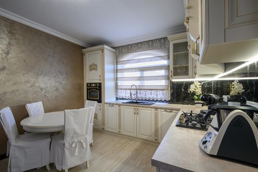 White rich classic cozy kitchen and dining room in city house interior