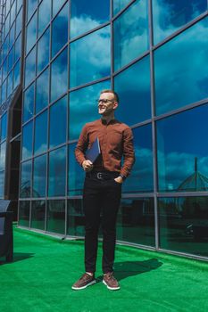 Cheerful businessman, formally dressed, pleased with received good news about contract details, sitting on office terrace with laptop, successful male entrepreneur
