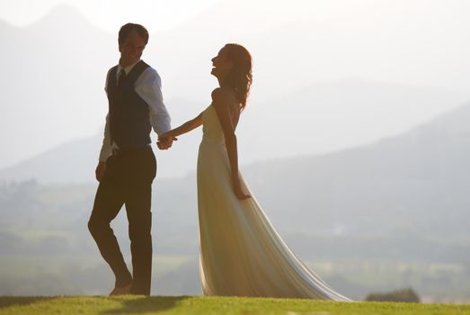 Love and laughter. A beautiful bride and groom walking hand in hand