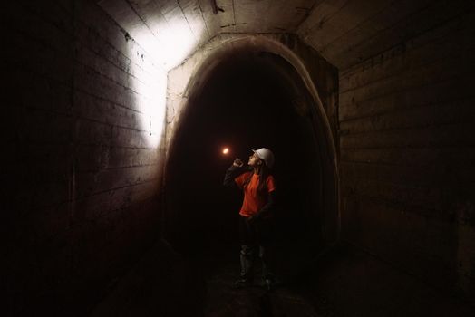 A young female digger with a flashlight explores the tunnel