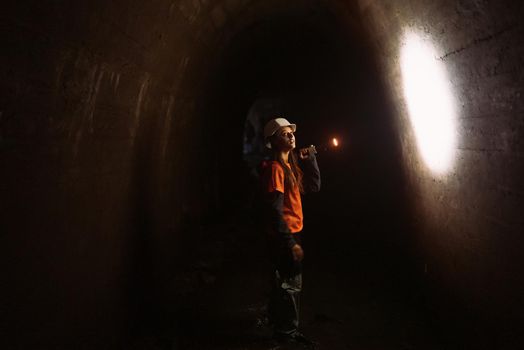 A young female digger with a flashlight explores the tunnel