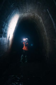A young female digger with a flashlight explores the tunnel
