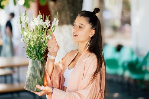 Woman puts a vase of flowers on a table in the yard
