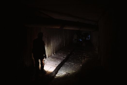 A young female digger with a flashlight explores the tunnel