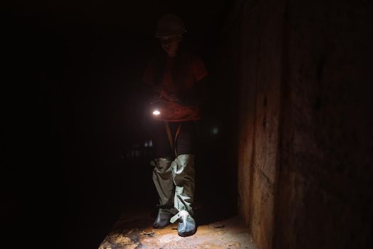 A young female digger with a flashlight explores the tunnel