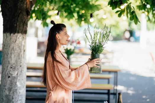 Woman puts a vase of flowers on a table in the yard