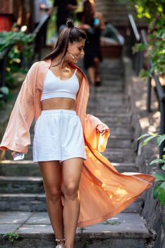 Young smiling woman on walking in the park wearing robe, summer day