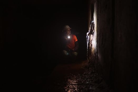 A young female digger with a flashlight explores the tunnel