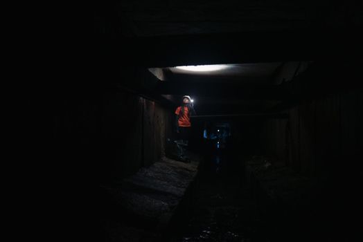 A young female digger with a flashlight explores the tunnel