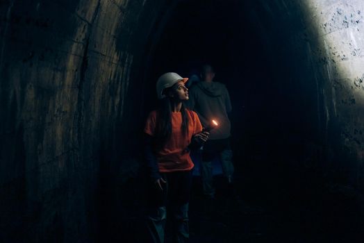 A young female digger with a flashlight explores the tunnel