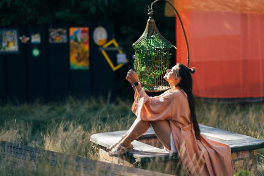 Side view of pleased brunette woman sitting on bench and enjoying the sunset