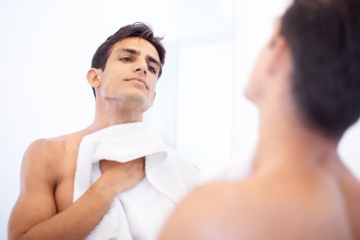 Loving his new shaver. A handsome man looking at himself in the mirror after shaving