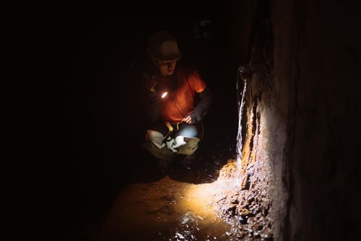 A young female digger with a flashlight explores the tunnel