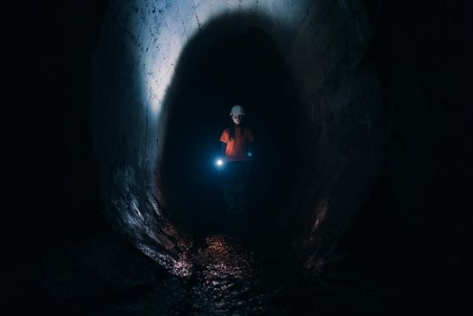 A young female digger with a flashlight explores the tunnel
