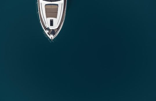 Aerial boat race. Luxury cruise trip. View from above of white boat on deep blue water. Aerial view of rich yacht sailing sea. Motor boat racing wave. Summer journey on luxury ship