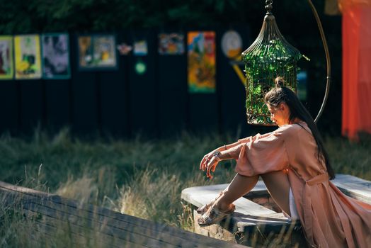 Side view of pleased brunette woman sitting on bench and enjoying the sunset