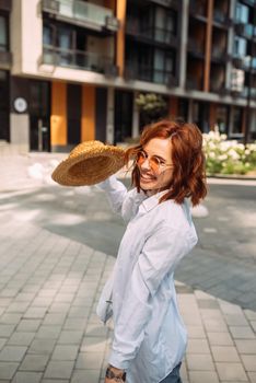 A red-haired woman poses for the camera on the street