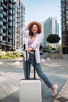 Stylish woman with suitcase looking at camera at the street