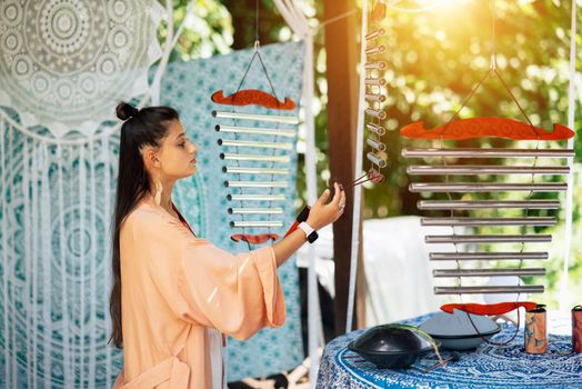 A young beautiful woman plays a musical instrument in the garden. Tubular bells