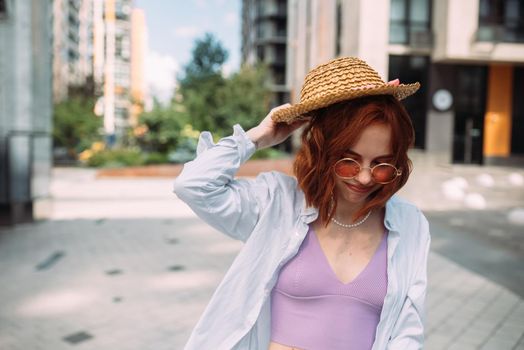A red-haired woman poses for the camera on the street