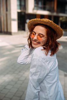 A red-haired woman poses for the camera on the street