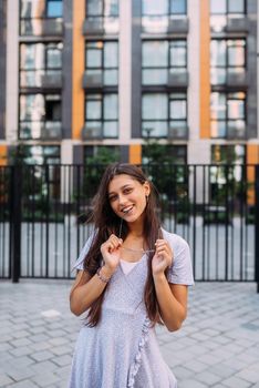 Summer time. Happy cheerful girl laughs on the background of large building in city.