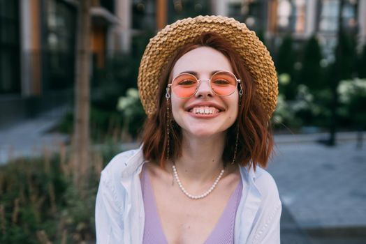 Close up portrait of a young caucasian woman with ginger red hair and toothy smile in outdoors