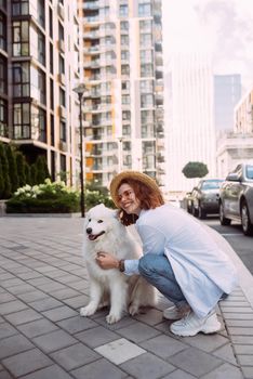 A young woman hugs a big dog at sunset in summer