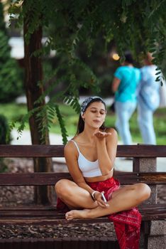 Happy girl using a smartphone in a city park sitting on a bench