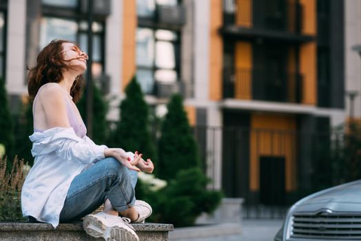 Young red-haired woman sitting in lotus position doing yoga exercise