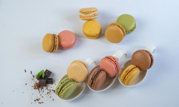 colorful macarons on white background with cup of coffee