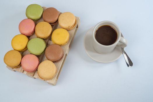 colorful macarons on white background with cup of coffee