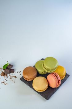 colorful macarons on white background with cup of coffee