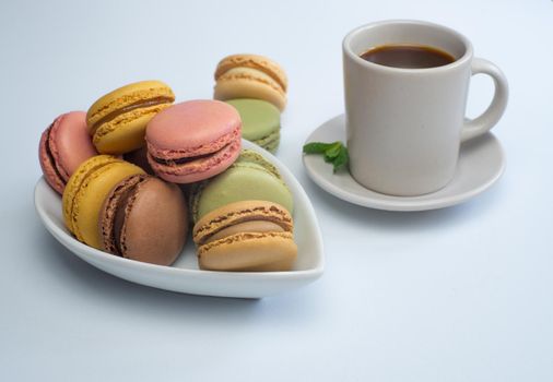 colorful macarons on white background with cup of coffee