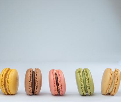 colorful macarons on white background with cup of coffee