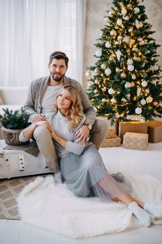 A happy couple in love - a man and a woman. A family in a bright New Year's interior with a Christmas tree.