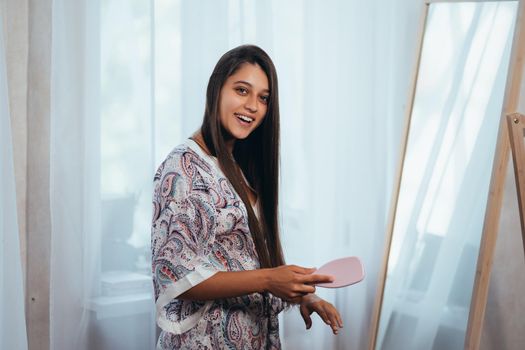 Woman combing hair in front of her mirror.