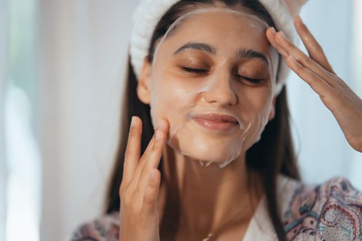 Young model applying cosmetic cream treatment on her face