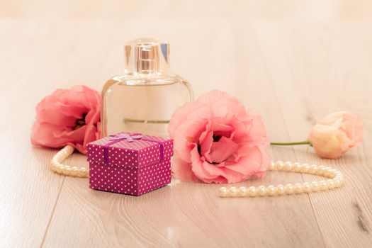Bottle of woman perfume with gift box and flowers on pink background. Holiday concept