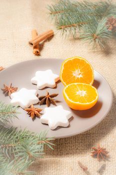 Gingerbread cookies in star shape on plate with cinnamon, star anise and natural fir tree branches with cones on sackcloth. Color toning effect.