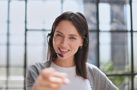 Smiling support phone woman operator in office. pointing at you