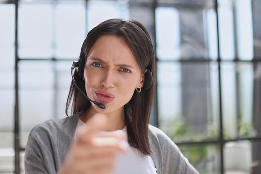 Smiling support phone woman operator in office. pointing at you