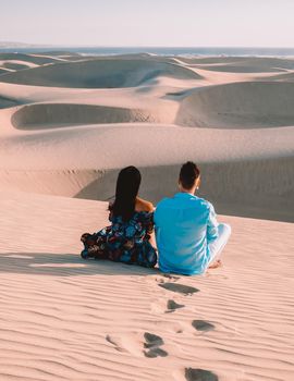 A couple walking at the beach of Maspalomas Gran Canaria Spain, men and woman at the sand dunes desert of Maspalomas Gran Canaria during vacation in Spain