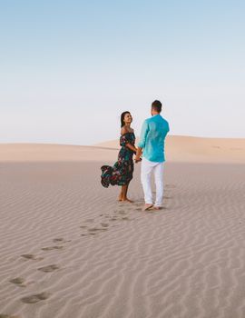 couple walking at the beach of Maspalomas Gran Canaria Spain, men and woman at the sand dunes desert of Maspalomas Gran Canaria